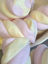Pastel-colored twisted candies in a white bowl on a marble surface